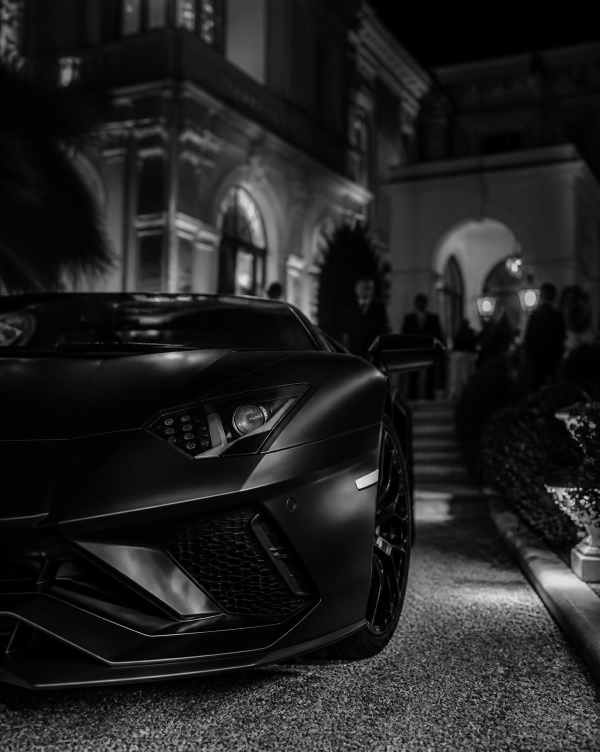 Supercar nera parcheggiata davanti a una villa di notte